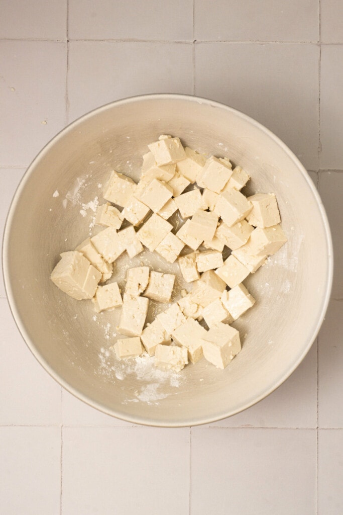 Tossing pressed and cubed tofu in olive oil and cornstarch. 