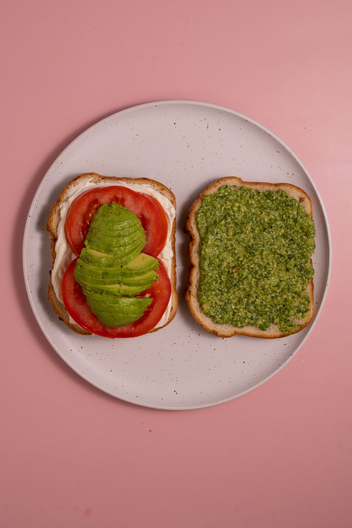 Layering avocado on top of tomato in veggie sandwich