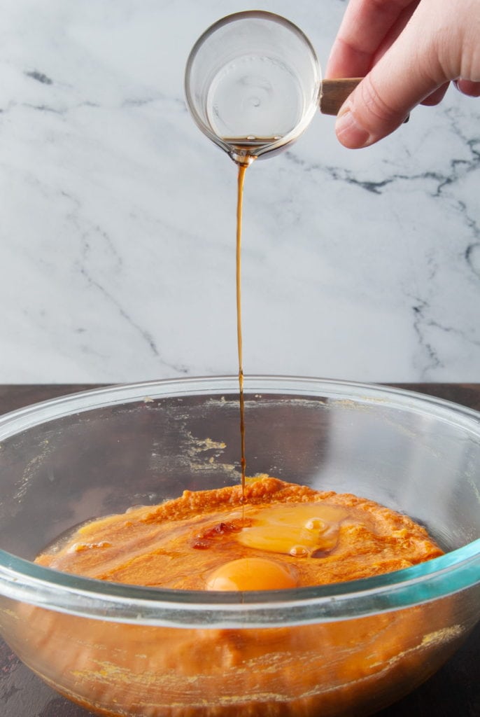 Adding vanilla extract to pumpkin muffin batter.