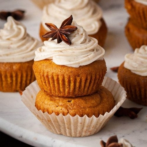 close up of two pumpkin muffins with cream cheese frosting stacked on top of each other