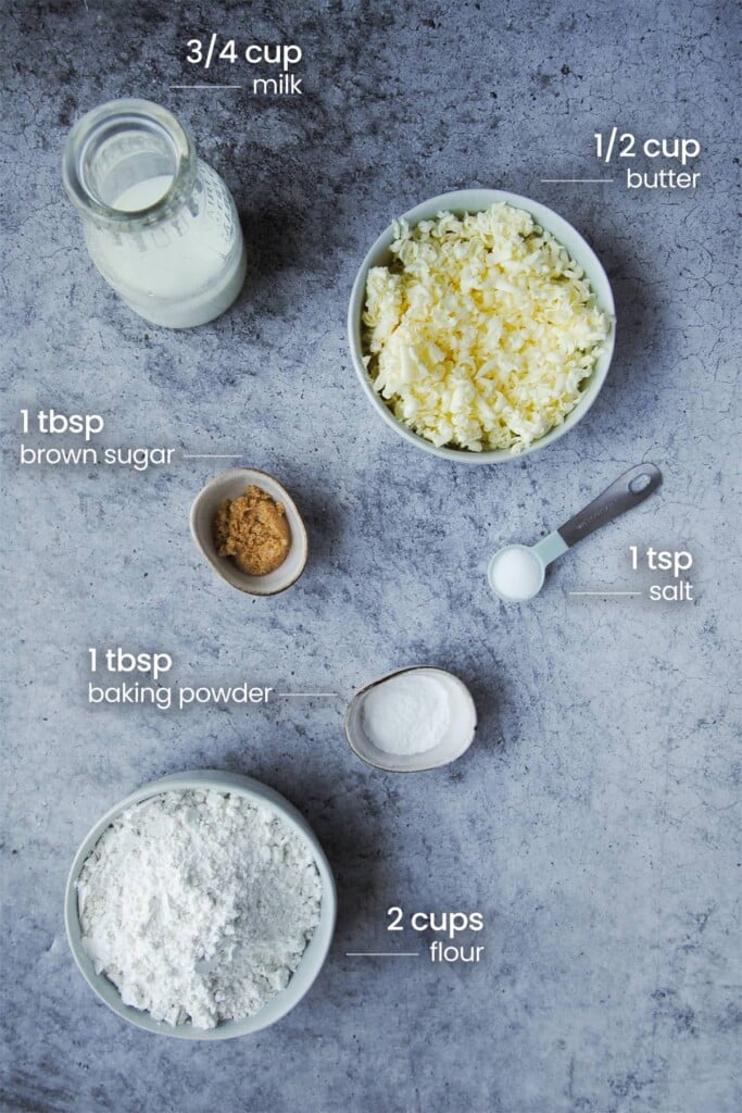 Overhead view of the ingredients needed to make southern USA style vegetarian biscuits - butter, milk, brown sugar, salt, baking powder, and flour.