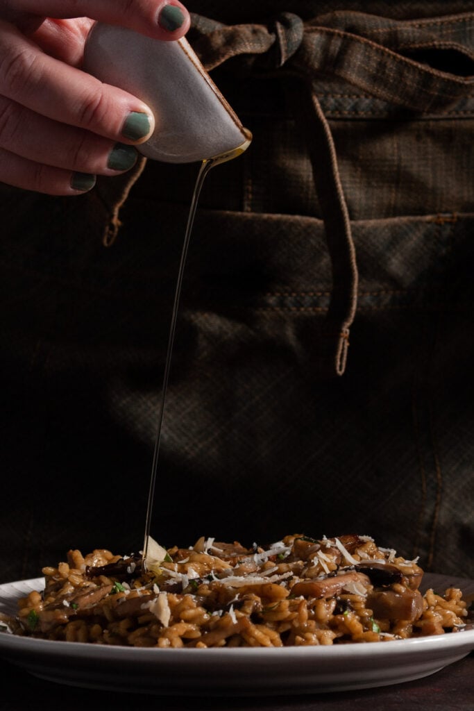 Adding truffle oil last to mushroom risotto.