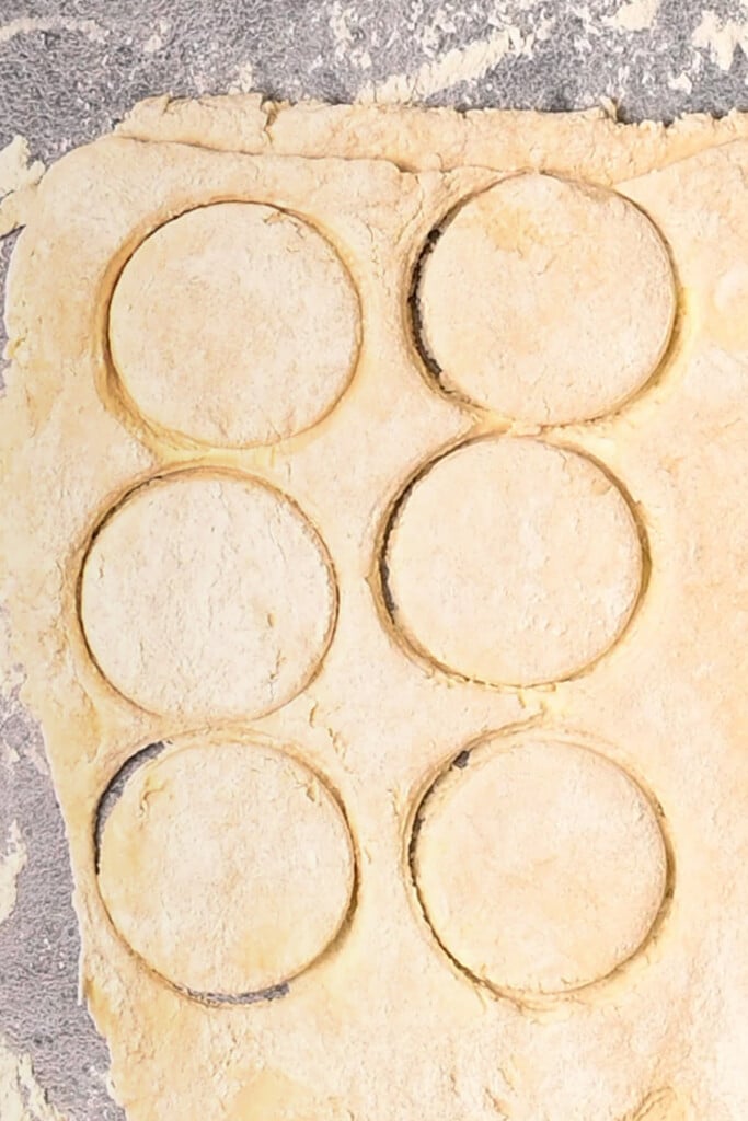 Biscuits cut out of a slab of dough using a mason jar for perfect circles.