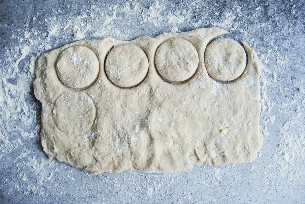 using a mason jar to cut circular shapes in biscuit dough