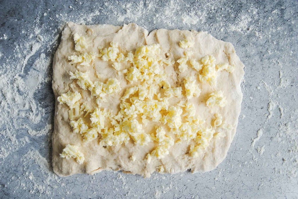 adding grated butter to flattened biscuit dough