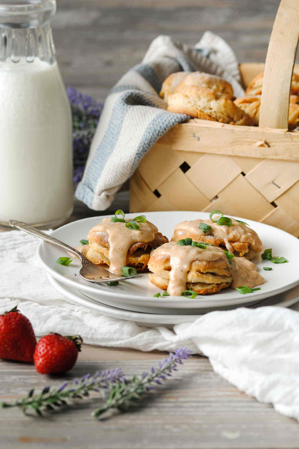 Vegetarian biscuits and gravy on a plate with more biscuits in a basket and a milk jug in the background.