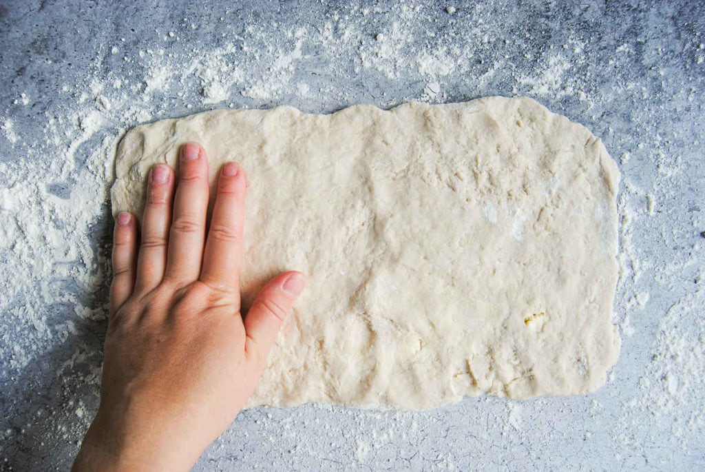 using hands to flatten out biscuit dough