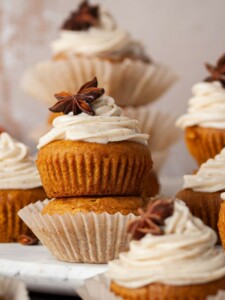 two pumpkin muffins stacked on top of eachother with the top oine having cream cheese frosting