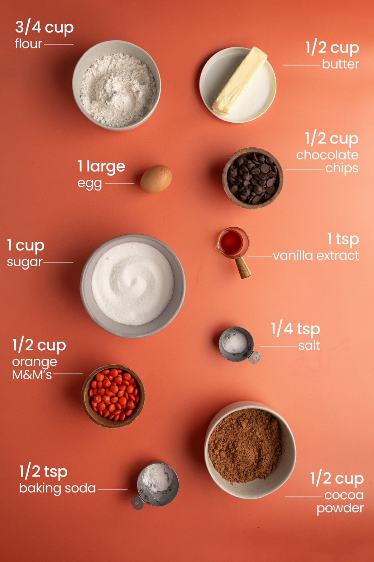 ingredients for Double Chocolate Halloween M&M Cookies - flour, butter, egg, chocolate chips, sugar, vanilla extract, orange M&Ms, salt, baking soda, cocoa powder