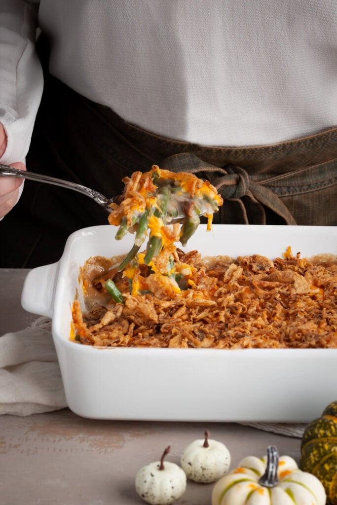 Using a large serving spoon to serve up green bean casserole made extra special with a secret ingredient.