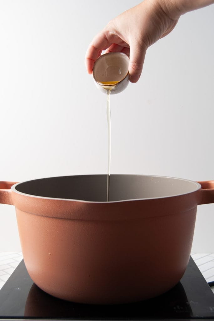 adding olive oil to a pot