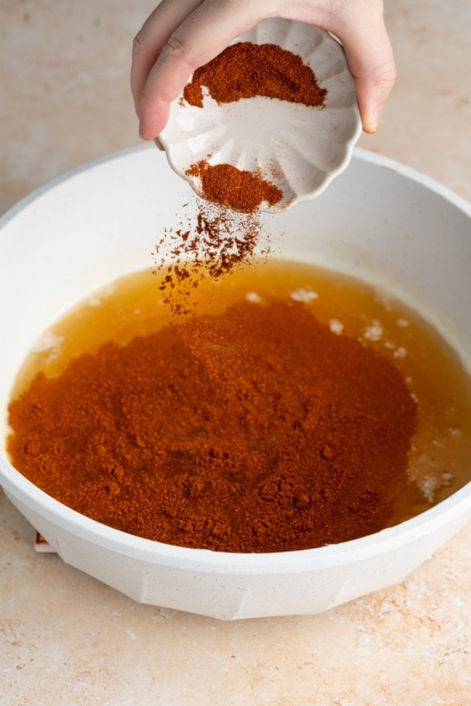 adding seasonings to enchilada sauce