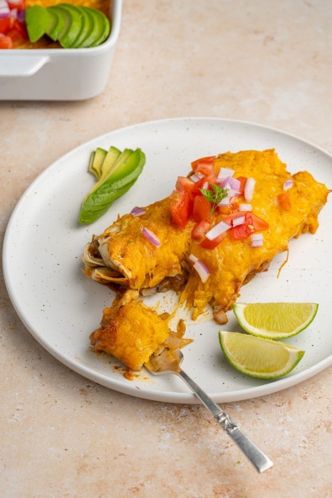 two enchiladas on a plate with one forkful on a fork