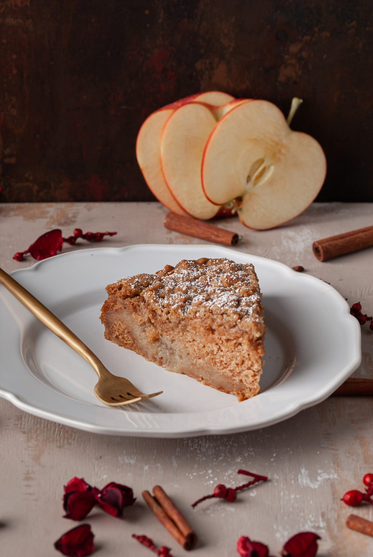 slice of super moist apple cake on a white plate with a gold fork