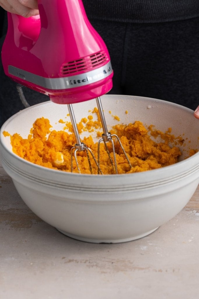 using a hand mixer to whip the sweet potato