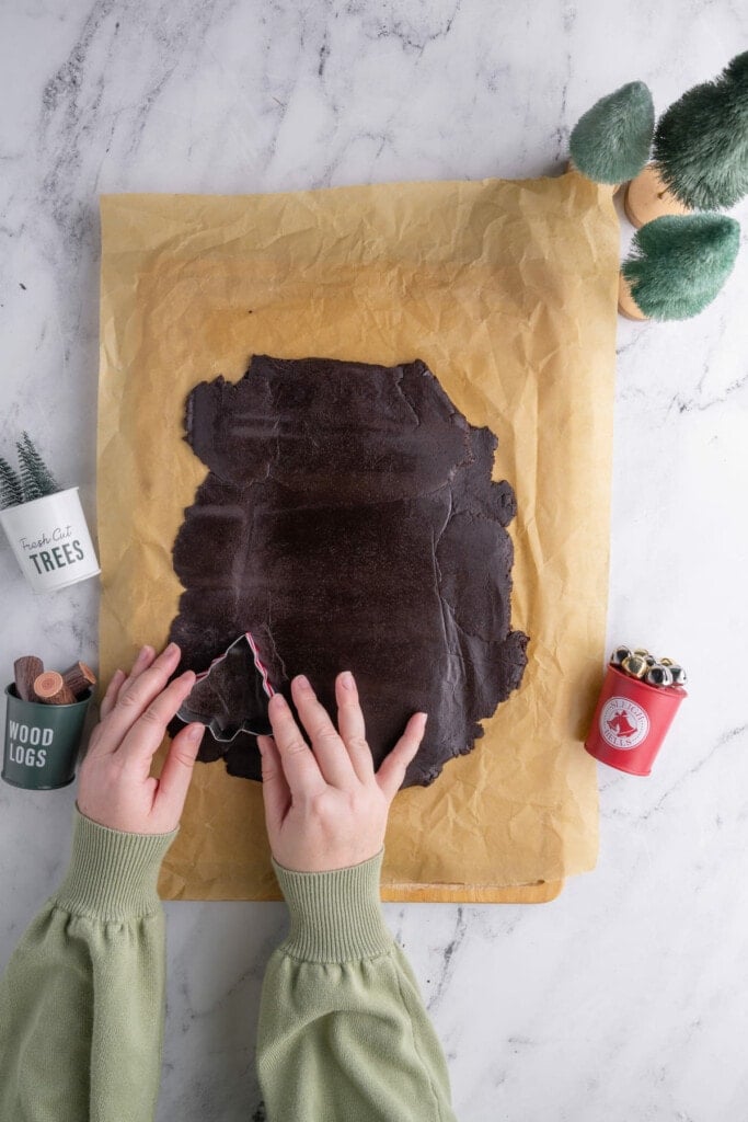 Using Christmas tree cookie cutter on chocolate peppermint cookie dough