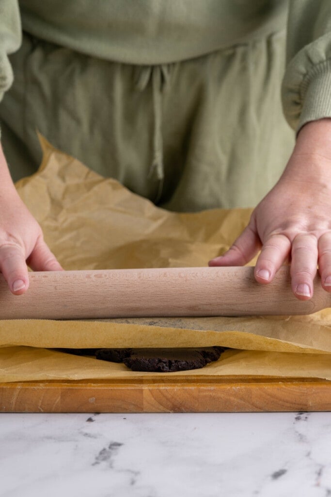 Rolling out chocolate peppermint cookie dough between two pieces of parchment paper