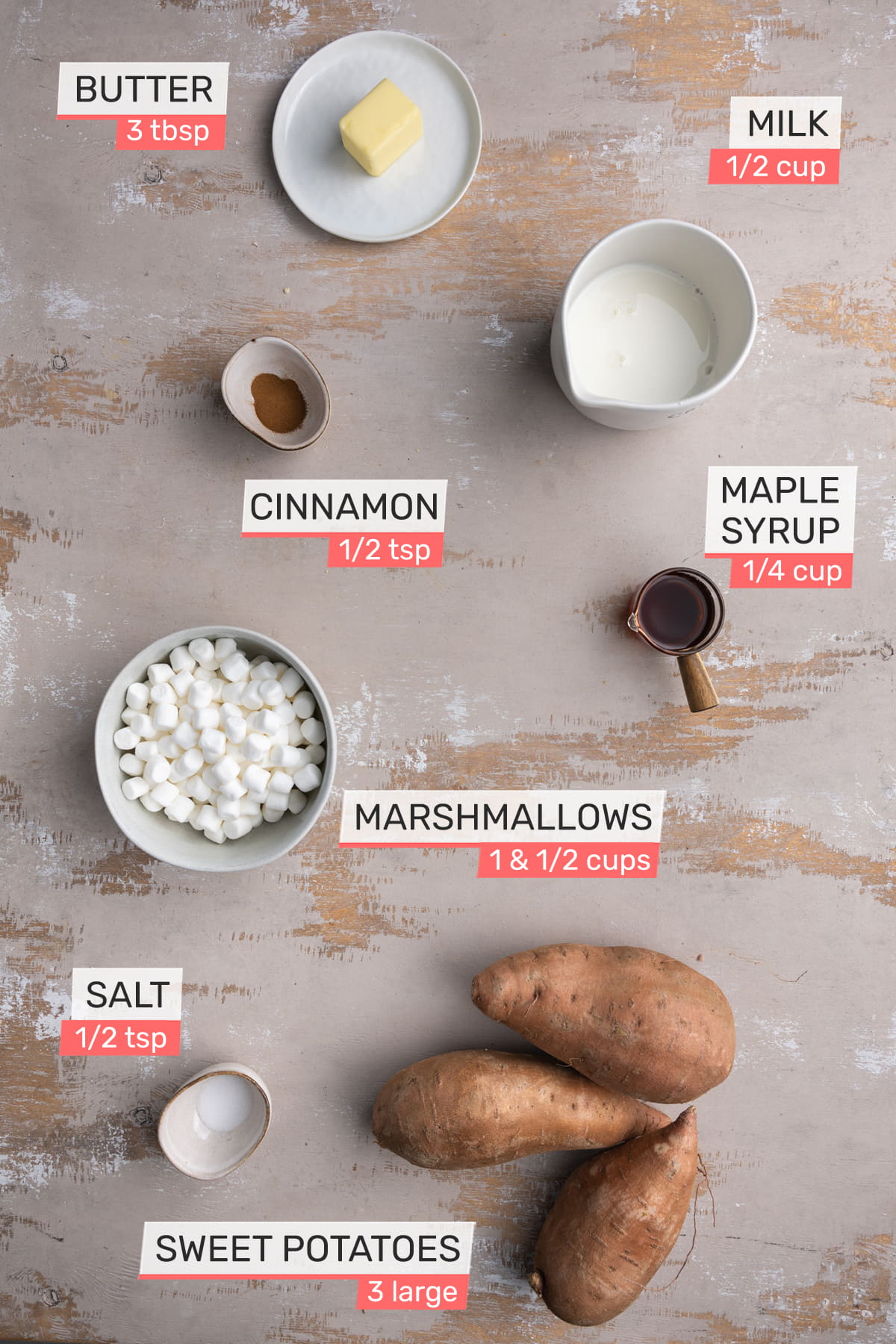 Overhead view of all ingredients for Maple Sweet Potato Casserole on a light wooden background - Butter, Milk, Cinnamon, Maple Syrup, Marshmallows, Salt, Sweet Potatoes