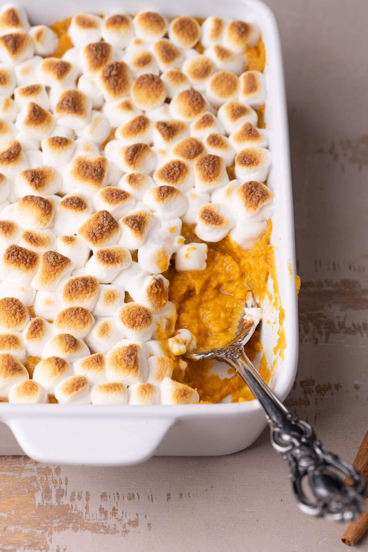 Using a large serving spoon to scoop out a serving of Sweet Potato Casserole for the Thanksgiving table.
