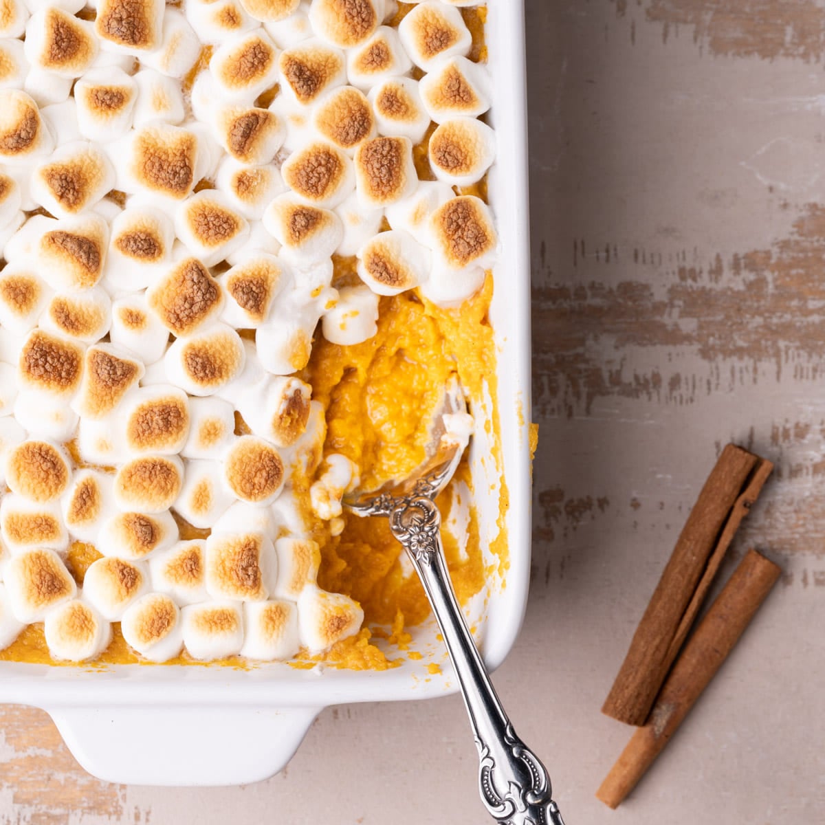 Maple Sweet Potato Casserole Featured Image Maple sweet potato casserole topped with toasted marshmallows with a serving taken out and a spoon in it.