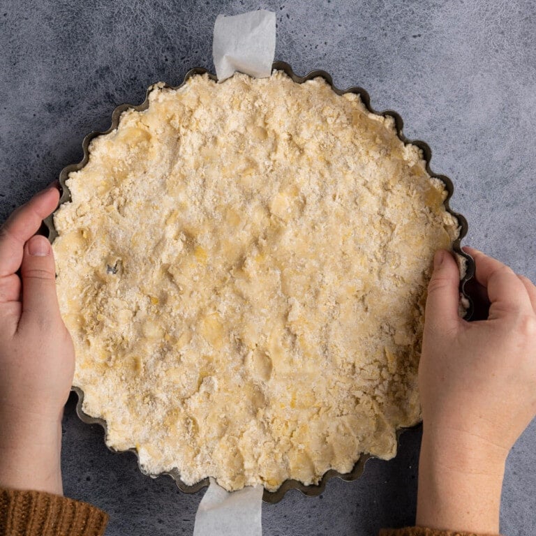 Using hands to press crust dough down into pie dish