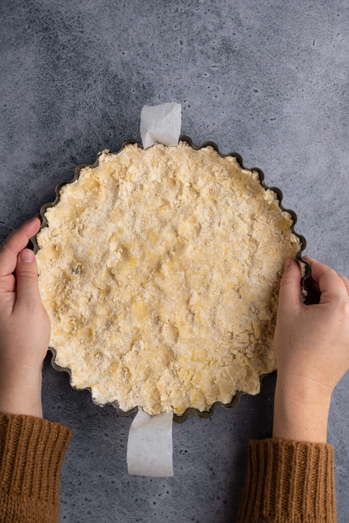 Using hands to press crust dough down into pie dish