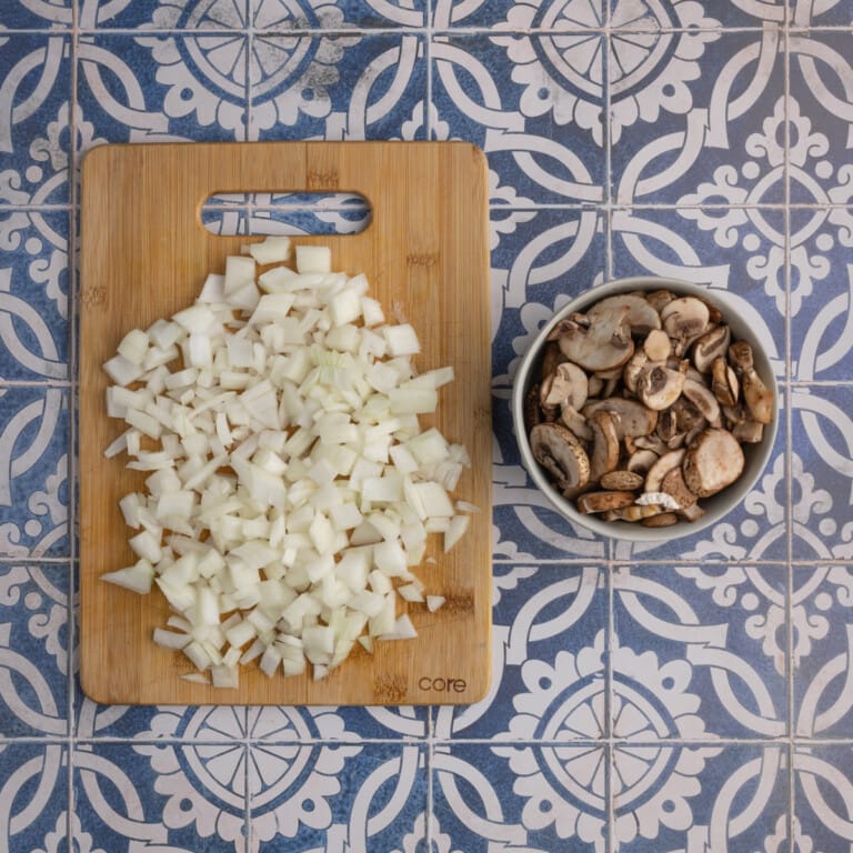 Diced onions and sliced mushrooms on a blue tile surface