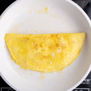 Flipping omelet to cook thoroughly on both sides.