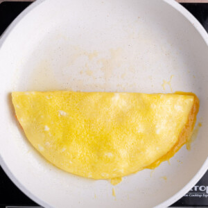 Folding eggs in half in a pan to form an omelet.