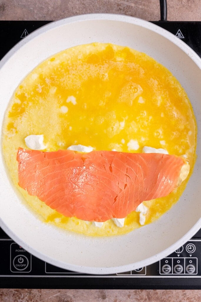 Lox on top of blobs of cream cheese in omelet.