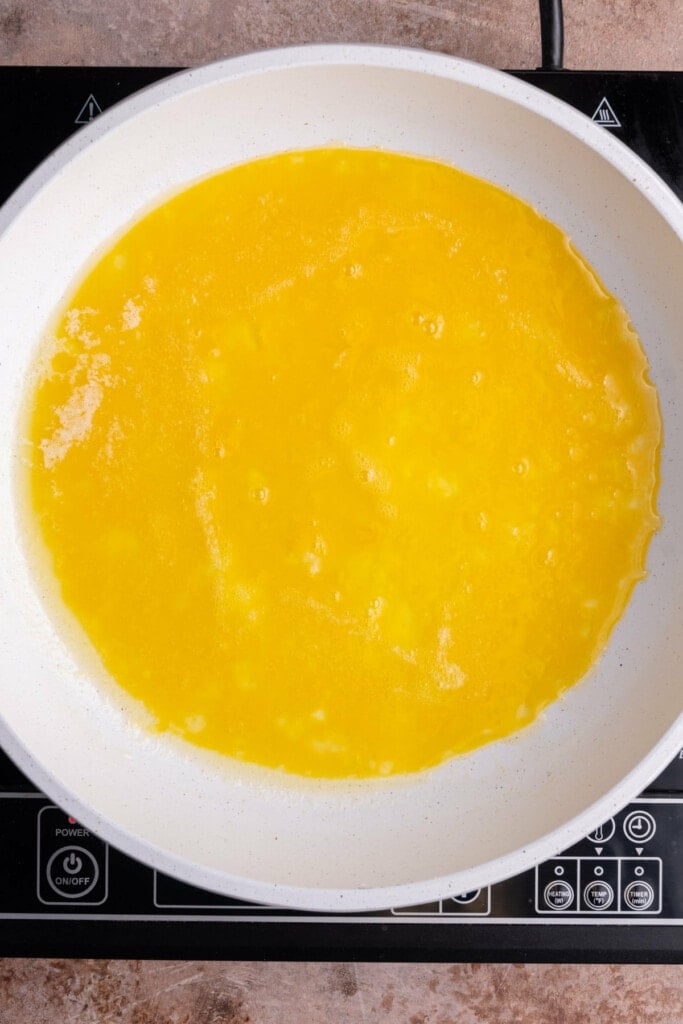 Beaten eggs cooking in a pan of hot butter.