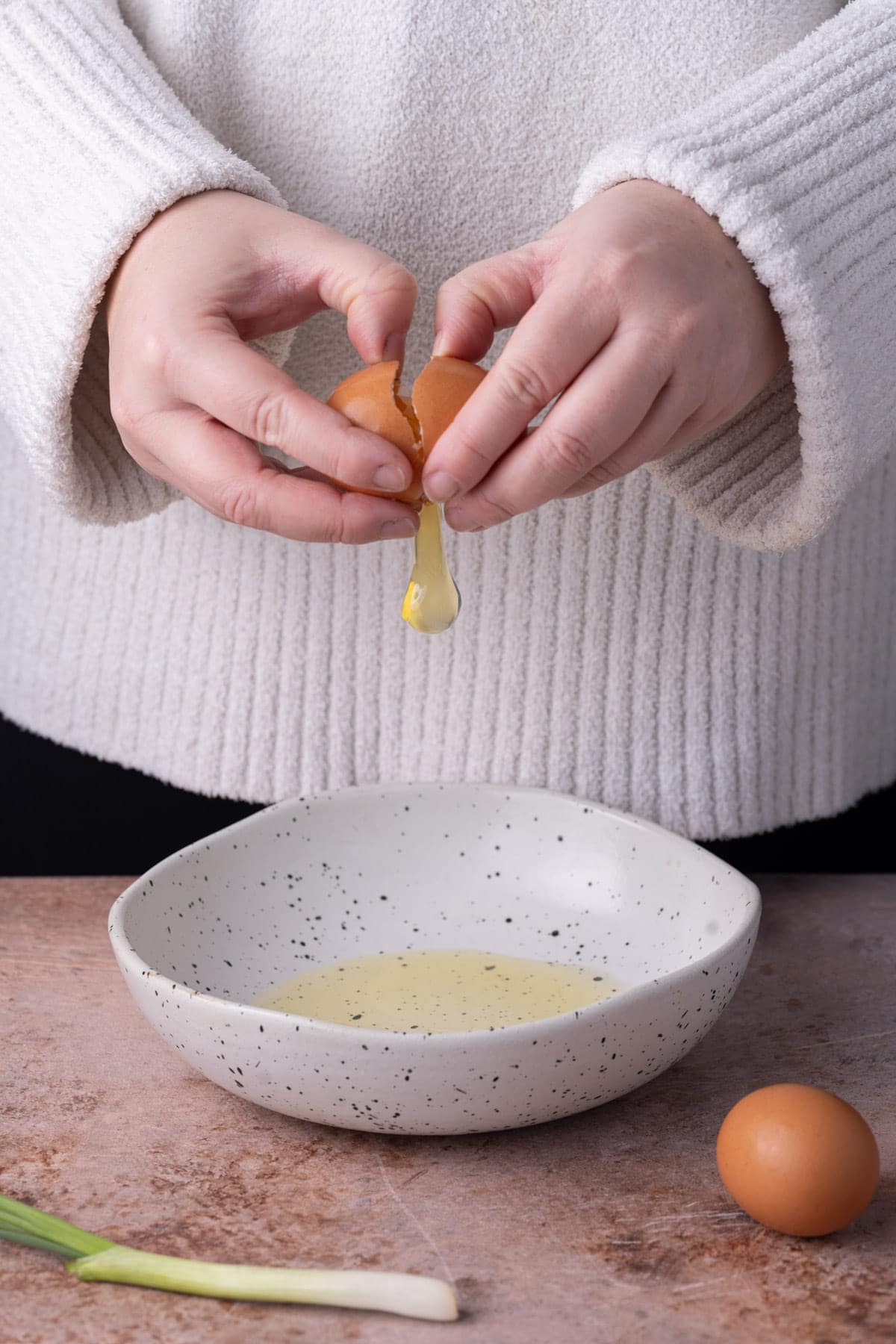 Cracking eggs into a shallow bowl to beat to make an omelet. 