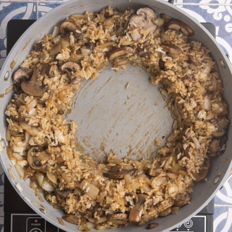 Mushroom fried rice pushed to the outer sides of the pan to create a well in the center