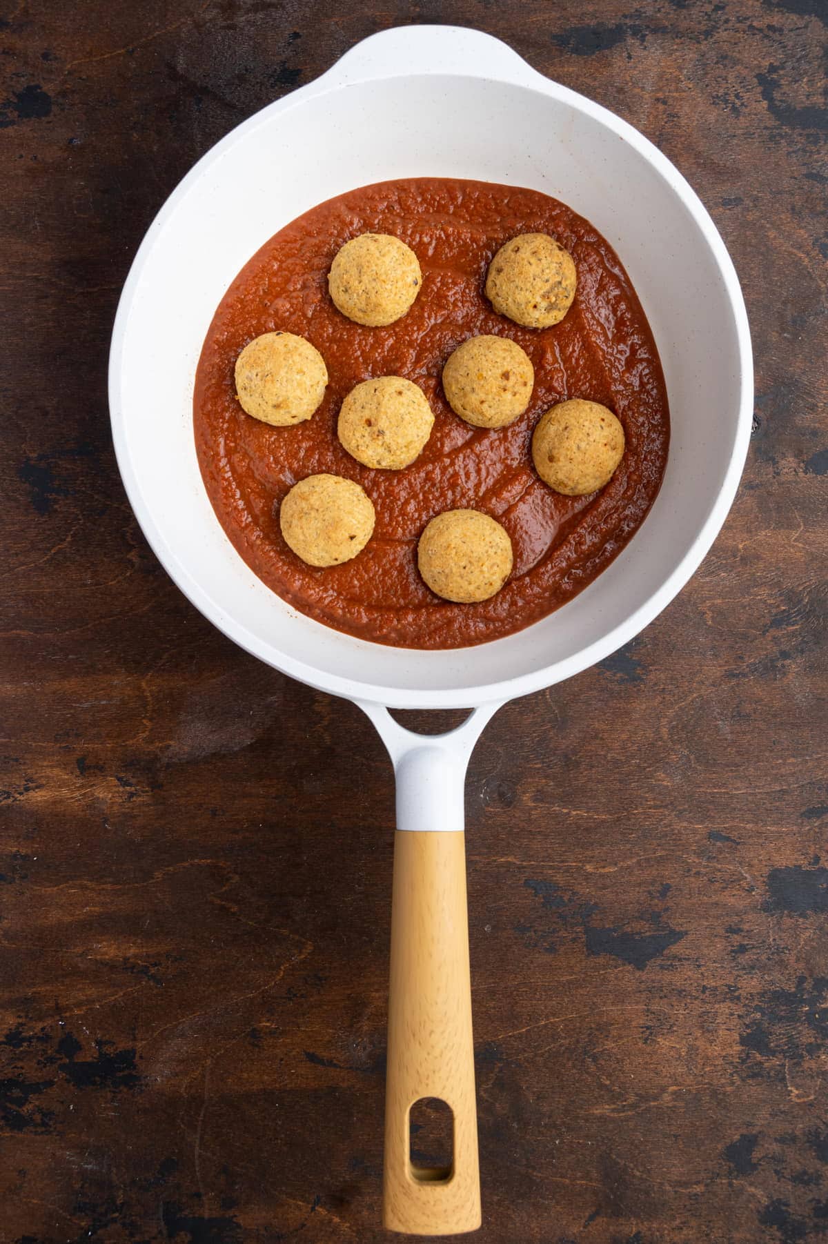 adding baked meatless meatballs to spaghetti sauce to cook