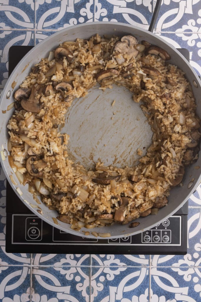 Making a well in the center of rice frying in a pan to add egg.