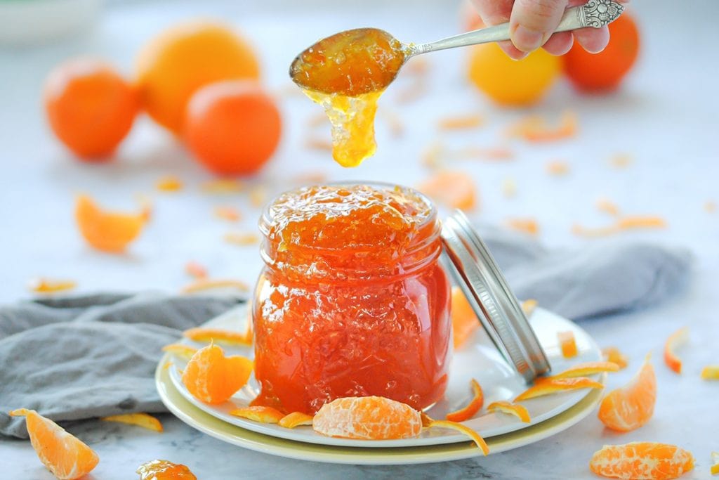 jar of marmalade with marmalade dripping off spoon into the jar