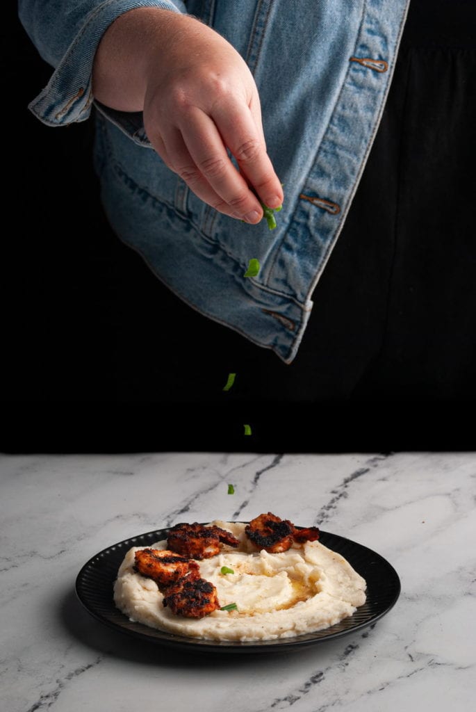 garnishing blackened shrimp with old bay mashed potatoes with scallions