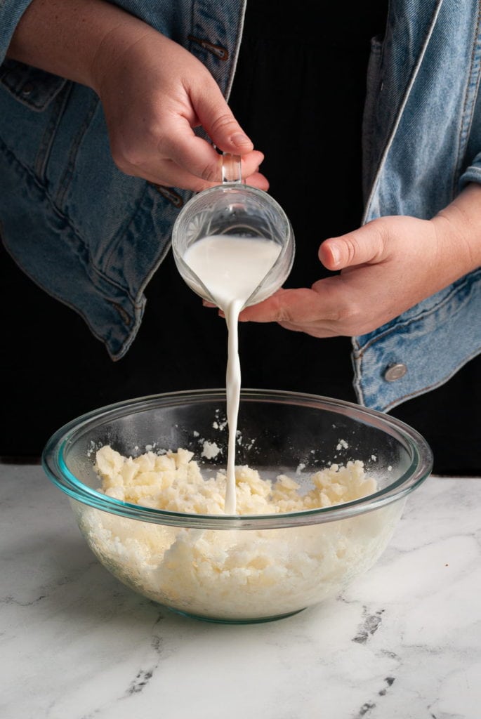 pouring milk into mashed potatoes