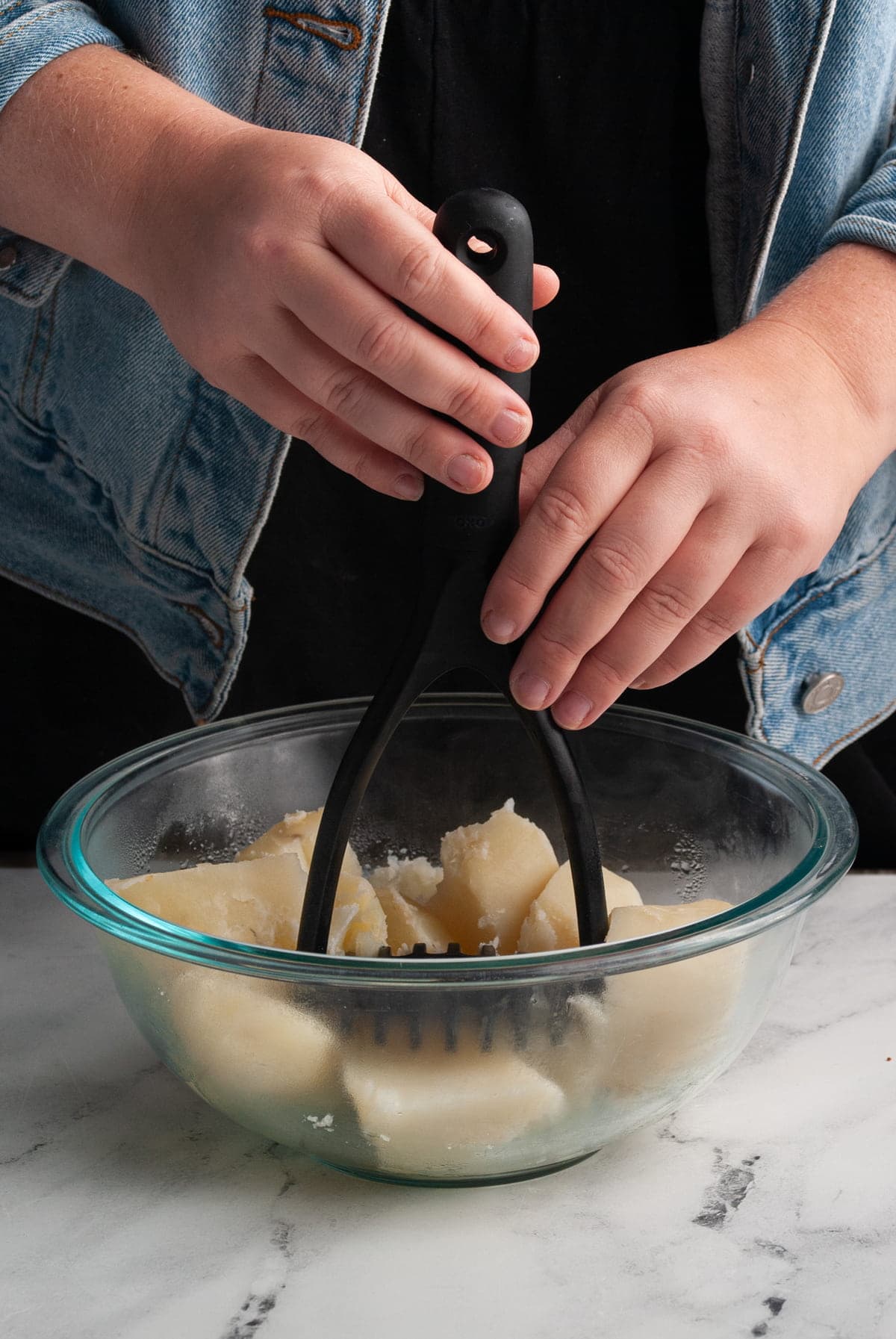 mashing potatoes in a glass bowl