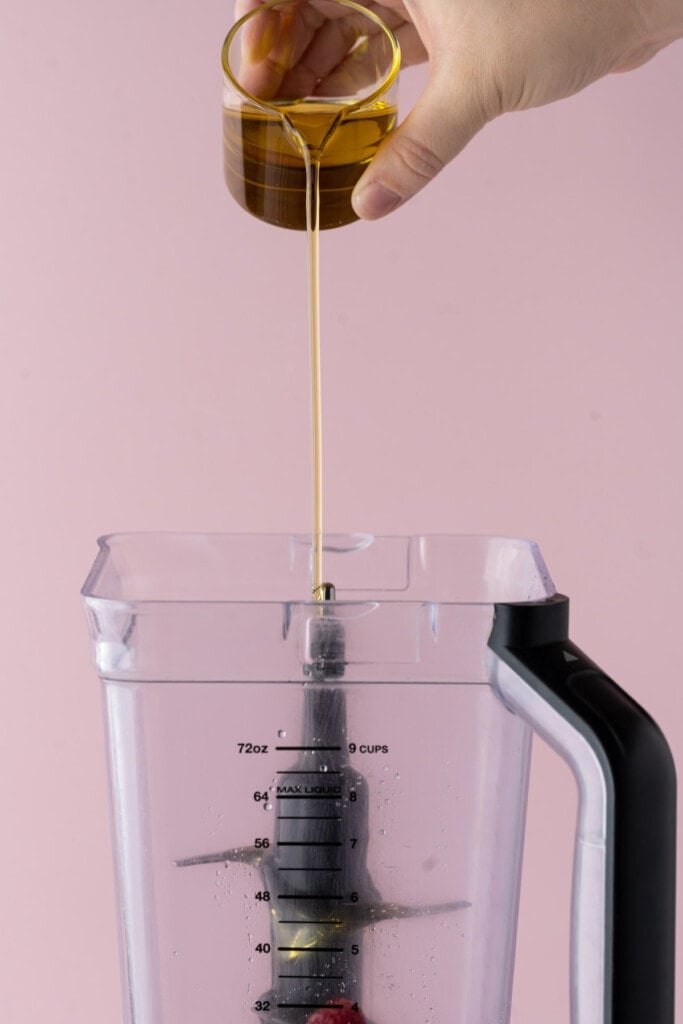 Adding olive oil to a blender to make vinaigrette.