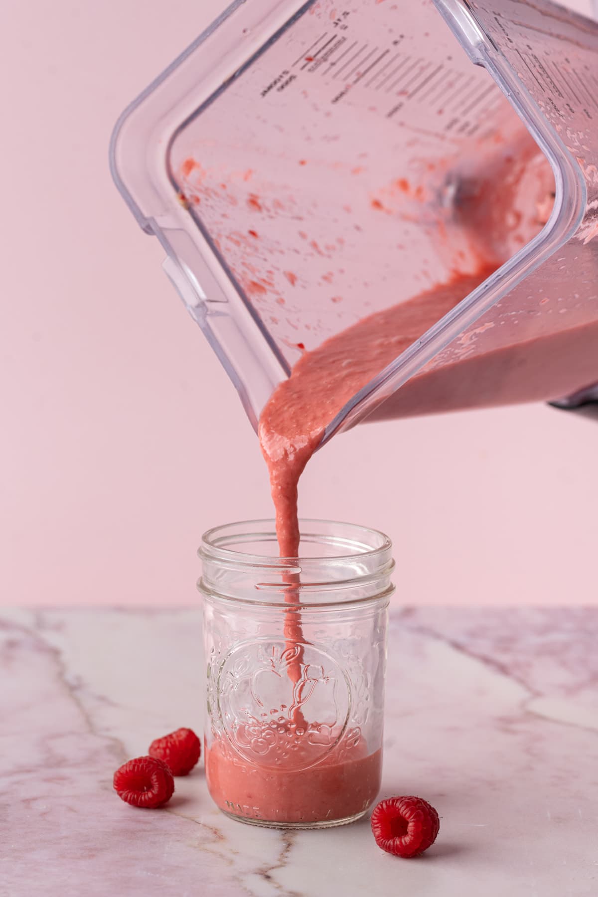 Pouring raspberry vinaigrette into a glass jar