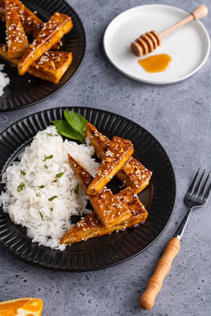 Crispy tofu coated in orange sauce plated with white rice