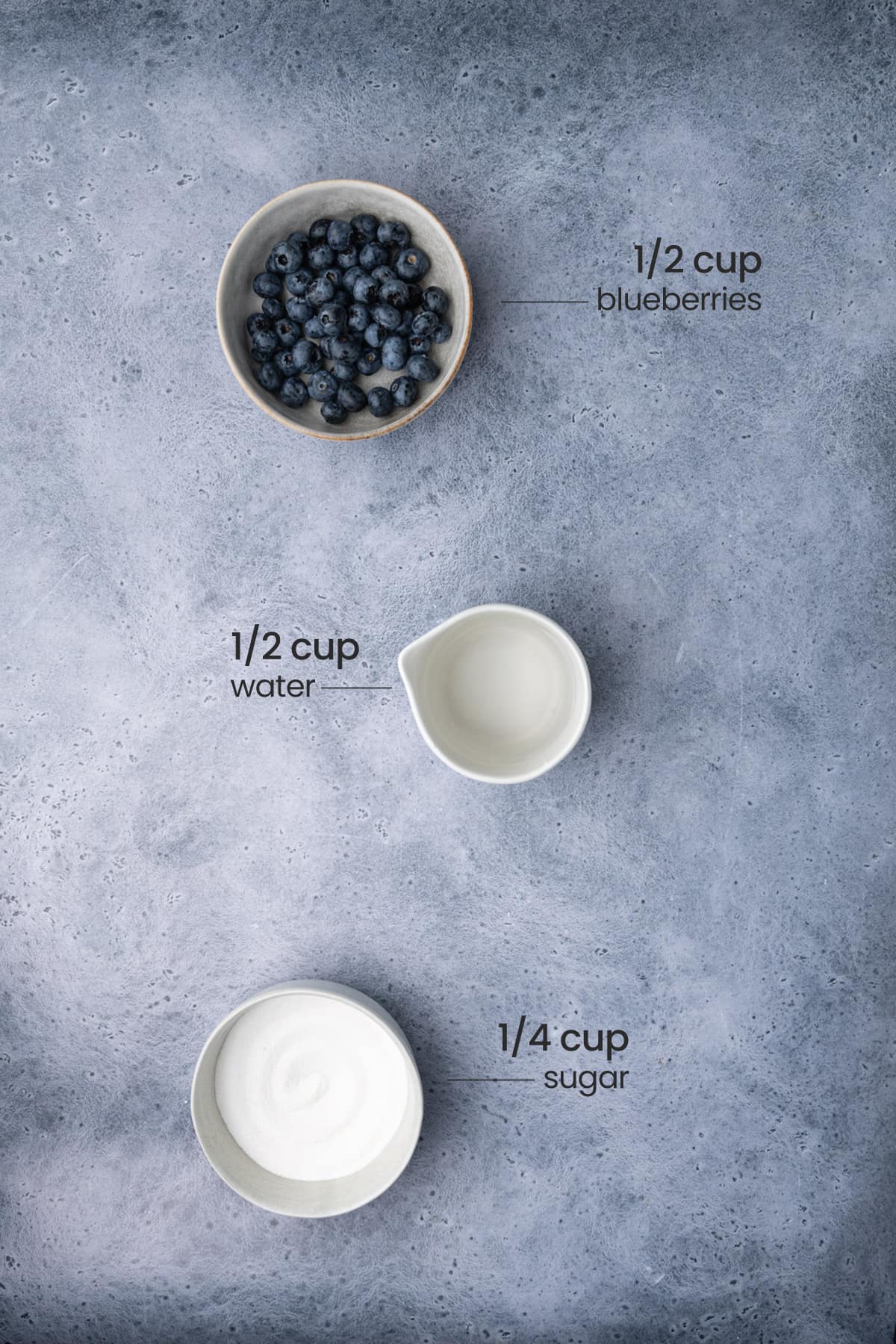 Overhead view of all ingredients for blueberry simple syrup - blueberries, water, and sugar.