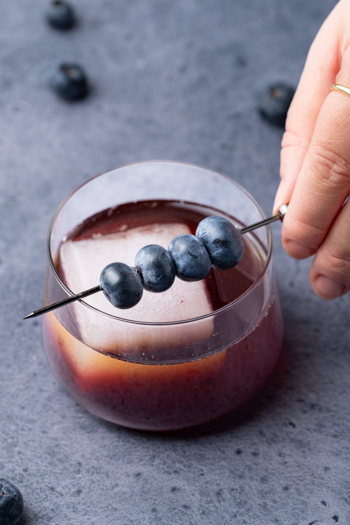 Garnishing the Whiskey Blues Cocktail with fresh blueberries. 