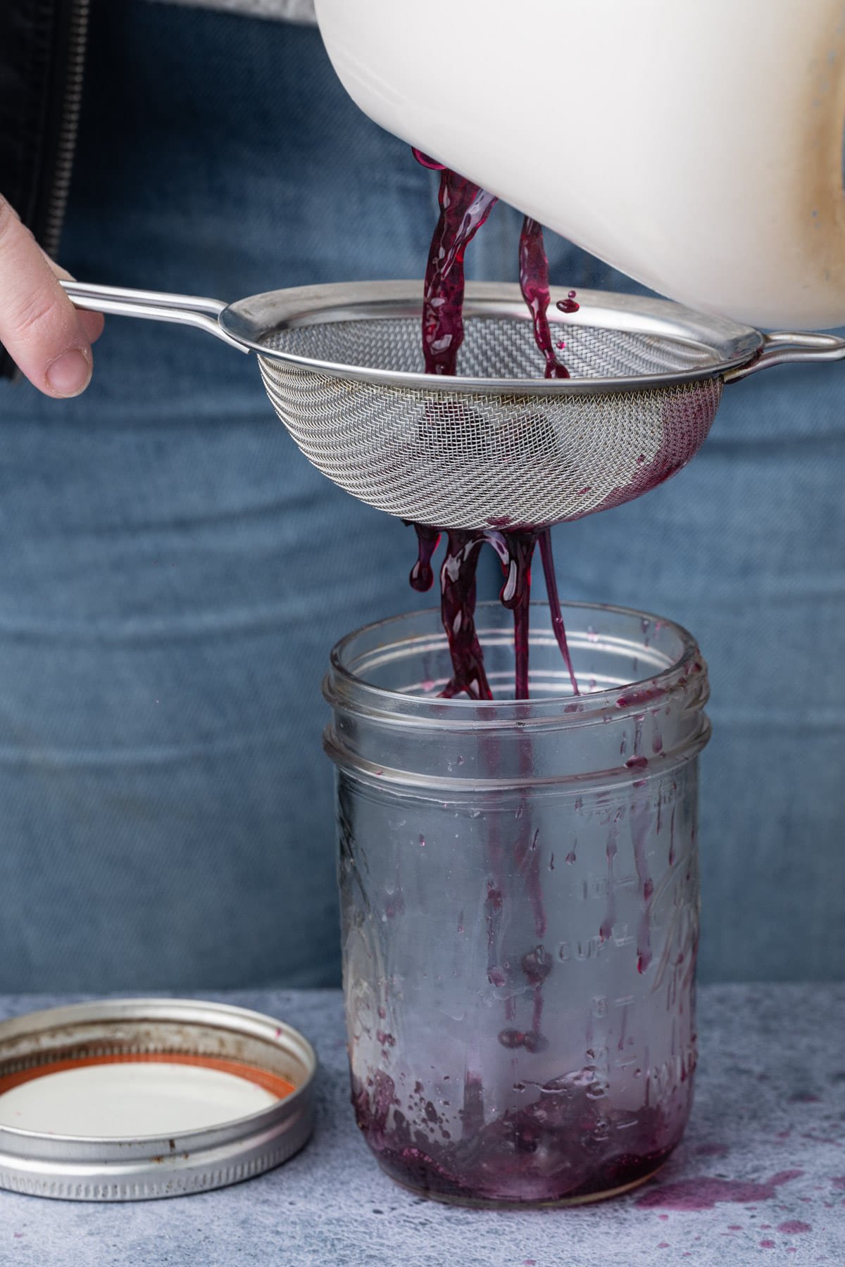 Passing blueberry simple syrup through a sieve to strain out the blueberries. 