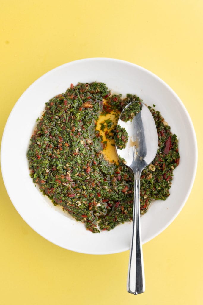 serrano pepper chimichurri in a shallow bowl with a serving spoon