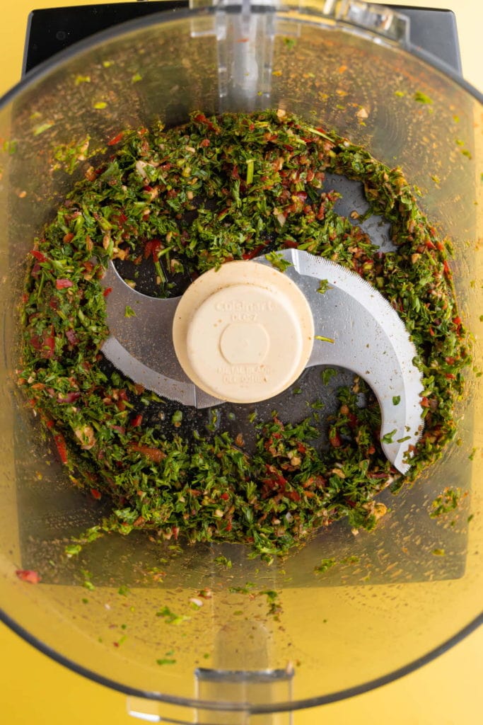 Ingredients for Serrano Pepper Chimichurri - red wine vinegar, fresh parsley, pepper, salt, garlic, serrano peppers, and paprika - in a blender (after blending).