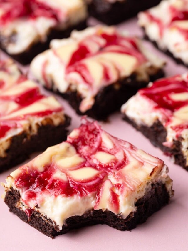 Raspberry Cheesecake Brownies laid out with a bite taken out of the front one.