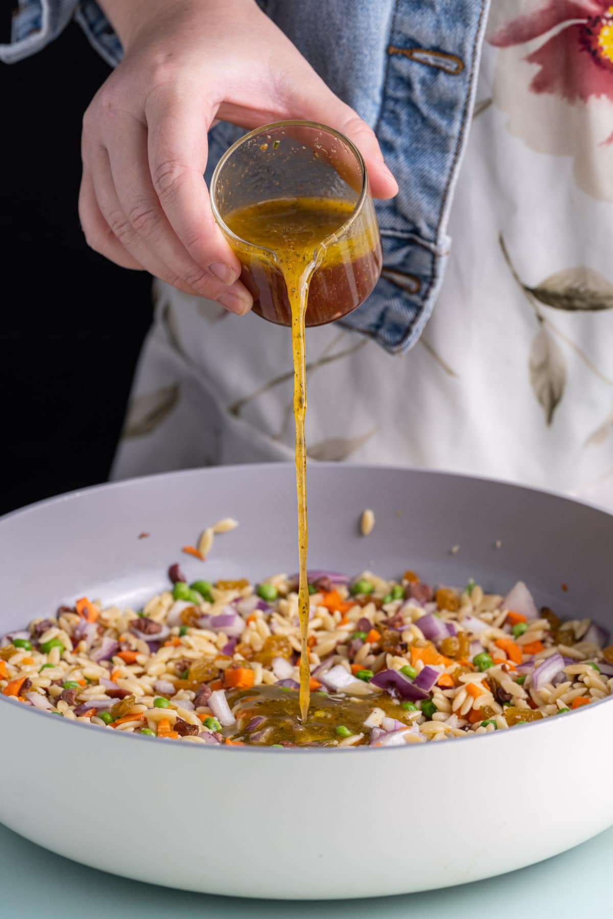 Tossing all ingredients for Rainbow Orzo Salad in a pan