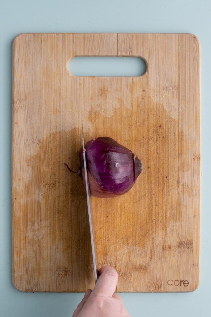 Chopping ends off of half of a red onion to easily peel it
